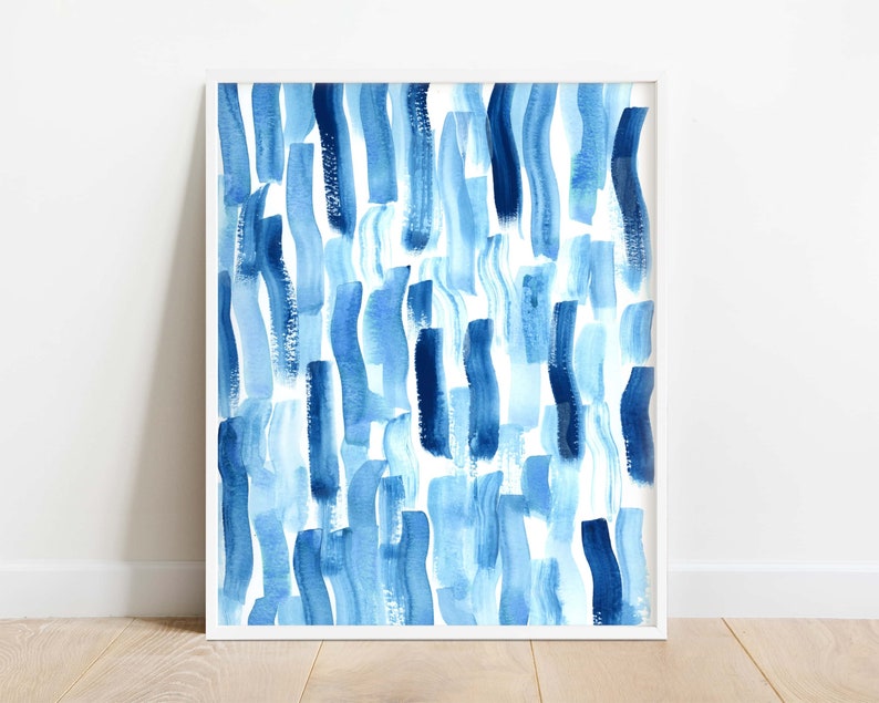 Puede incluir: Impresi&oacute;n art&iacute;stica enmarcada con un dise&ntilde;o abstracto de pinceladas verticales en tonos azules sobre un fondo blanco. La obra de arte se presenta en un marco blanco, ofreciendo un aspecto contempor&aacute;neo y minimalista. Ideal para la decoraci&oacute;n del hogar u oficina.