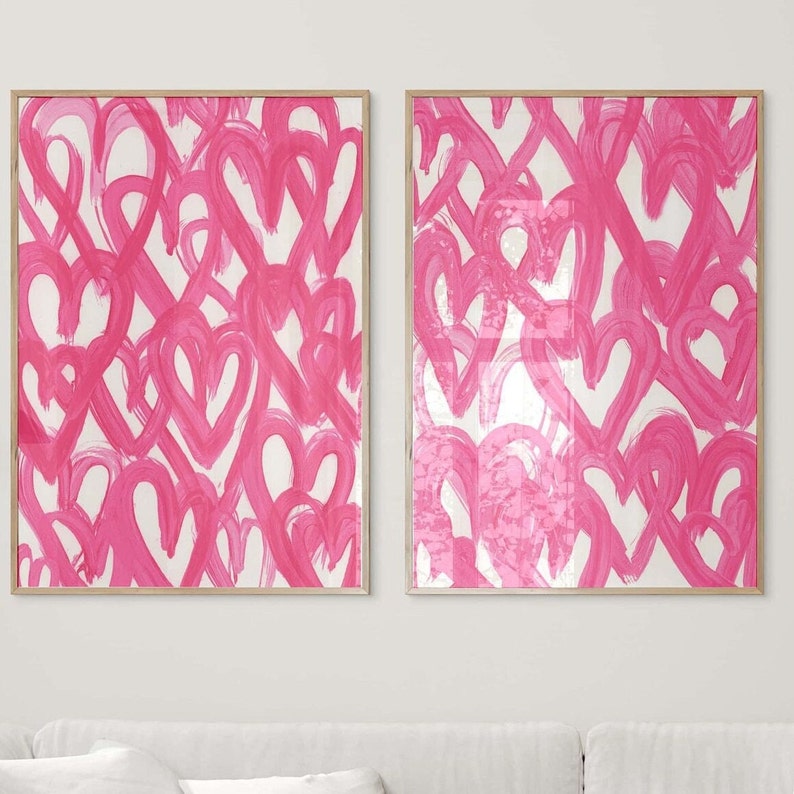 May include: Two framed prints with a pink and white abstract design of overlapping hearts. The prints are in a modern style and would look great in a living room or bedroom.