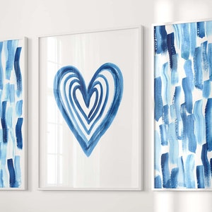 Puede incluir: Conjunto de tres l&aacute;minas enmarcadas. Dos l&aacute;minas muestran pinceladas verticales en tonos azules sobre fondo blanco. La l&aacute;mina central presenta un coraz&oacute;n azul. Los marcos son blancos.