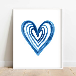 Puede incluir: Impresi&oacute;n art&iacute;stica enmarcada con un dise&ntilde;o de coraz&oacute;n azul en acuarela. El coraz&oacute;n est&aacute; compuesto por pinceladas superpuestas en diferentes tonos de azul, creando un efecto texturizado sobre un fondo blanco. La obra est&aacute; enmarcada en un marco blanco.
