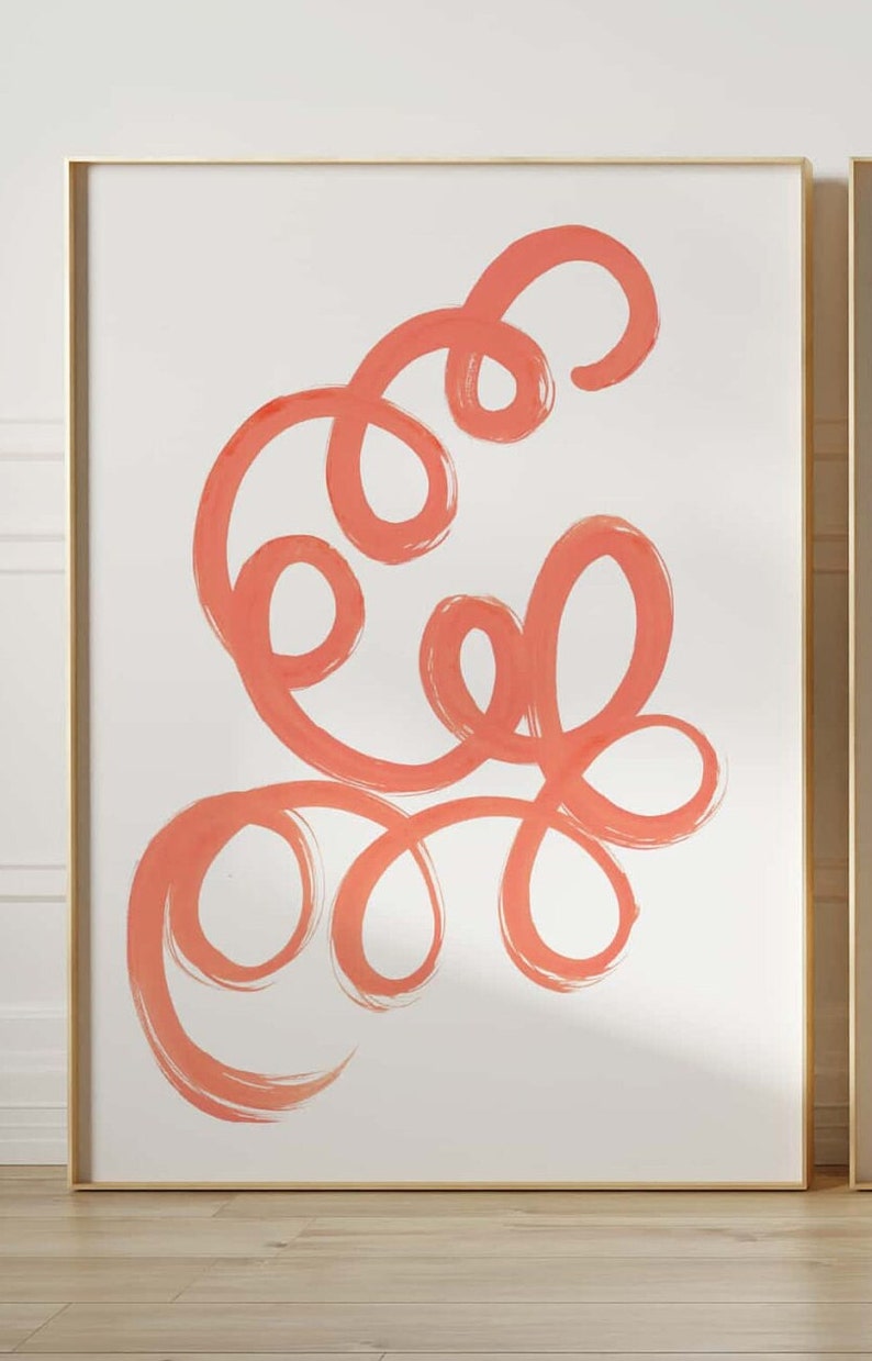 K&ouml;nnte beinhalten: Abstrakter Kunstdruck mit einem korallenfarbenen Design aus wirbelnden Linien und Schleifen auf wei&szlig;em Hintergrund. Der Druck ist in einem goldenen Rahmen gerahmt.