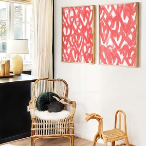 May include: Two framed abstract paintings with pink hearts on a white background, a wicker rocking horse, and a wicker chair with a green velvet cushion.