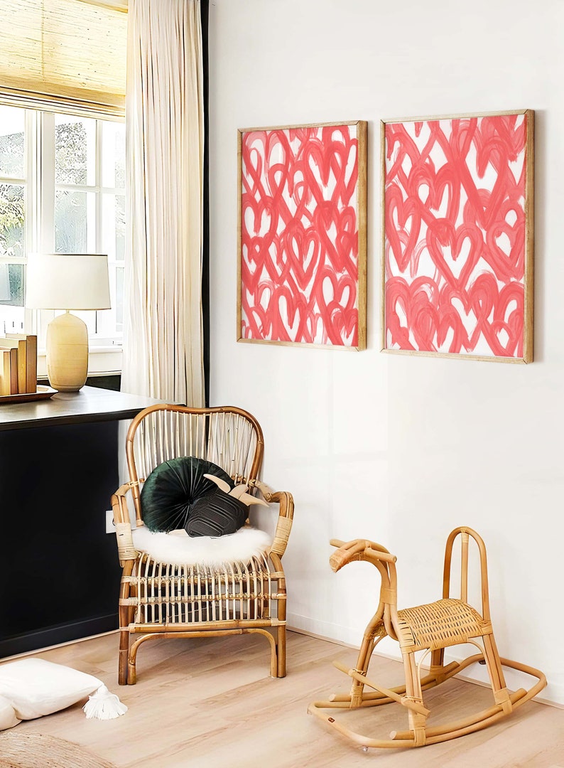 May include: Two framed abstract paintings with pink hearts on a white background, a wicker rocking horse, and a wicker chair with a green velvet cushion.