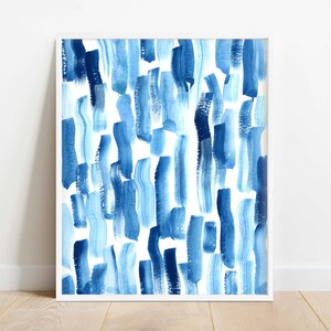 Puede incluir: Una impresi&oacute;n art&iacute;stica enmarcada con pinceladas verticales en tonos azules sobre un fondo blanco. La obra de arte est&aacute; en un marco blanco y se muestra sobre un suelo de madera.