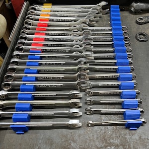 May include: A drawer full of wrenches organized by size with blue plastic holders. The wrenches are all silver and have the word "CRAFTSMAN" printed on them.