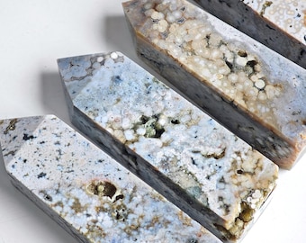 May include: A collection of polished stone obelisks. The obelisks have a rectangular base and a pointed top. The stones are primarily blue and white with brown and tan inclusions. The obelisks are arranged diagonally across the frame.