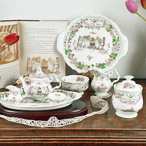 May include: A collection of Brambly Hedge porcelain tableware, including a teapot, creamer, sugar bowl, serving tray, and a large decorative plate. The set features floral and whimsical illustrations with a soft color palette, perfect for a tea party.