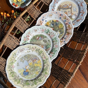 Puede incluir: Conjunto de cuatro platos decorativos con temática de Beatrix Potter que presentan diferentes ilustraciones y los años 1996, 1997, 1998 y 1999. Los platos se muestran en una cesta de mimbre.