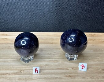 May include: Two dark blue glass spheres with a glittery finish, sitting on clear stands. The spheres are labeled A and B.