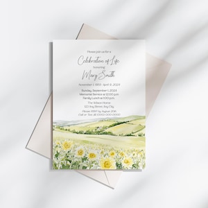 May include: A white invitation card with text for a Celebration of Life honoring Mary Smith. The card features a watercolor painting of a field of sunflowers and rolling hills. The invitation is placed on top of a light beige envelope.