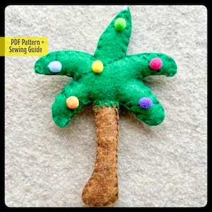 May include: A felt palm tree ornament with a brown trunk and green leaves. The leaves are decorated with colorful felt balls in shades of red, orange, yellow, green, blue, and purple.