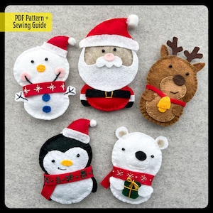 May include: Five felt Christmas ornaments: a snowman with a red and white scarf, Santa Claus with a white beard, a reindeer with a brown body and a gold bell, a penguin with a red and white scarf, and a polar bear holding a green gift box.