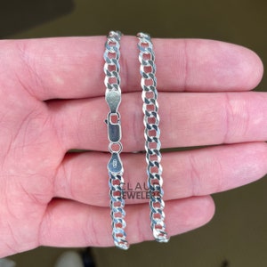 May include: A silver curb chain necklace with a lobster clasp. The chain is about 20 inches long and has a width of about 5 millimeters.