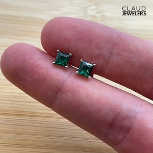 May include: A pair of silver stud earrings with square green gemstones.