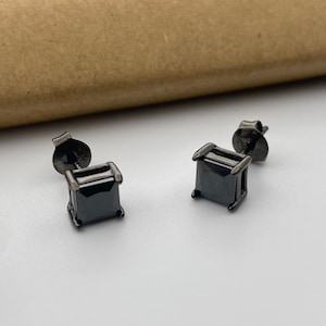 May include: A pair of black square stud earrings with black cubic zirconia stones.