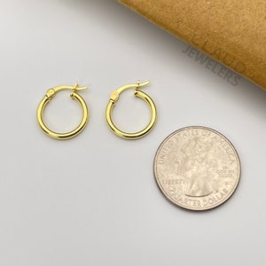 May include: A pair of gold hoop earrings. The earrings are small and delicate, and they are shown next to a US quarter for size comparison.