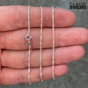 May include: A silver chain necklace with a lobster clasp. The chain is a delicate, twisted design.