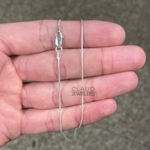 May include: A silver snake chain necklace with a lobster clasp.