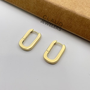 May include: A pair of gold-toned hoop earrings with a rectangular shape. The earrings are simple and elegant.