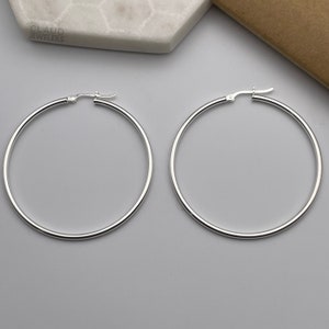 May include: A pair of silver hoop earrings. The hoops are large and circular, with a simple design.