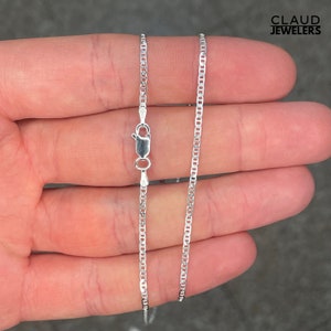 May include: A silver chain necklace with a lobster clasp. The chain is a delicate, flat, oval-shaped link style.