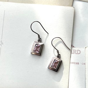 May include: A pair of silver dangle earrings with a rectangular pink stone in each earring.