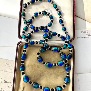 May include: A blue and green glass bead necklace with black beads. The necklace is in a velvet-lined jewelry box.