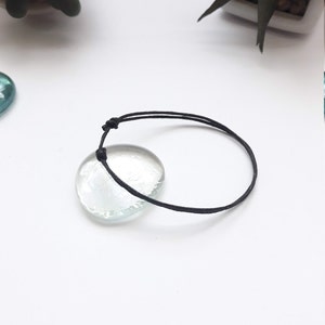 May include: A simple black string bracelet with a knot at the end.