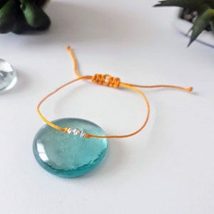 May include: A simple yellow string bracelet with a silver bead accent.