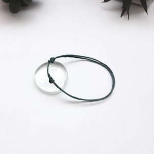 Puede incluir: Un sencillo brazalete de cuerda verde oscuro con un nudo en cada extremo.