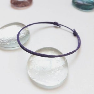 Könnte beinhalten: Ein lilafarbenes Armband aus Schnur mit einem einfachen Knotenverschluss.