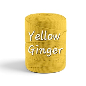 May include: A cylindrical spool of mustard yellow macrame cord wound in a tight, continuous pattern. The text Yellow Ginger is printed in white, sans-serif letters across the center of the cord spool, clearly visible against the yellow surface.