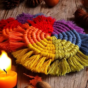 May include: A colorful rainbow macrame wall hanging with a spiral design and fringe. The wall hanging is made with cotton cord and is a vibrant and unique piece of home decor.