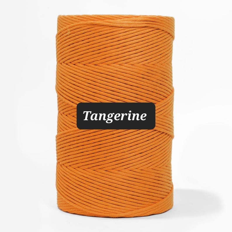 May include: A spool of tangerine-colored cord, tightly wound and textured. The word "Tangerine" is displayed on a black rectangle. The cord is a vibrant orange hue, suitable for various crafting projects.