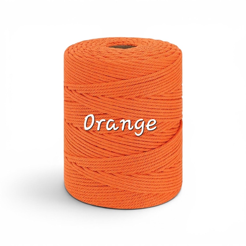 May include: A cylindrical spool of bright orange macrame cord wound tightly in a continuous spiral pattern. The word Orange is printed in white script font across the center of the spool, which features a hollow circular core at the top.