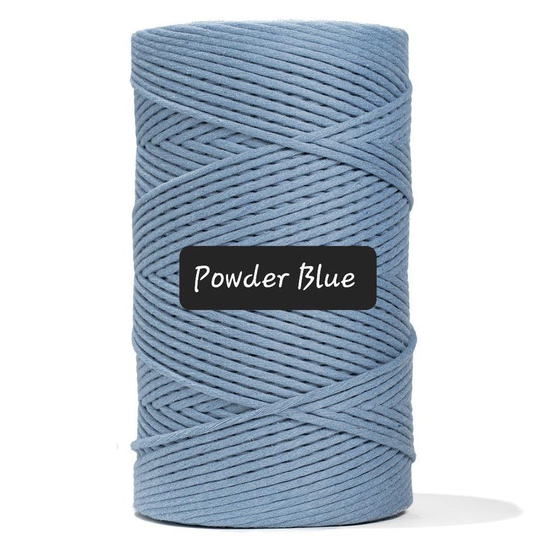 May include: A cylindrical spool of powder blue macrame cord. The cord is tightly wound, creating a textured surface. The text "Powder Blue" is displayed on a black label.