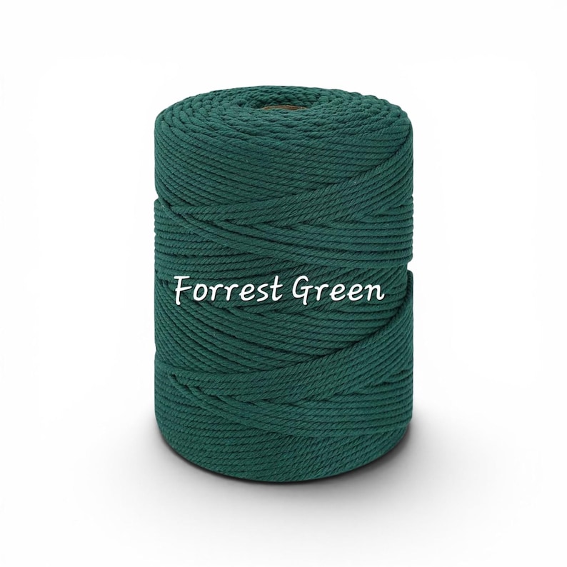 May include: A cylindrical spool of dark green macrame cord wound in a tight, continuous spiral pattern. The text "Forrest Green" is printed in white, cursive lettering across the center of the spool, clearly visible against the dark cord.