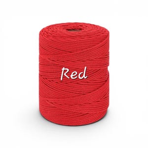 May include: A cylindrical spool of vibrant red macrame cord featuring a tightly wound, multi-strand twisted texture. The word Red is printed in a white, cursive-style font across the center of the spool, clearly visible against the cord.