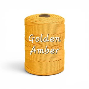 May include: A cylindrical spool of golden amber colored cord featuring a tightly wound, multi-strand twisted texture. The words Golden Amber are printed in white, sans-serif font across the center of the spool against the yellow cord.