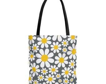 May include: A gray tote bag with a white daisy pattern and yellow centers. The bag has black handles.