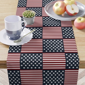 May include: A red, white, and blue table runner with a checkered pattern of American flags. The runner is made of fabric and has a smooth texture.