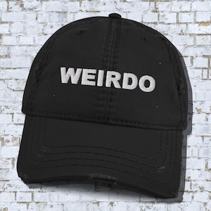 May include: A black distressed baseball cap with the word "WEIRDO" embroidered in white on the front.