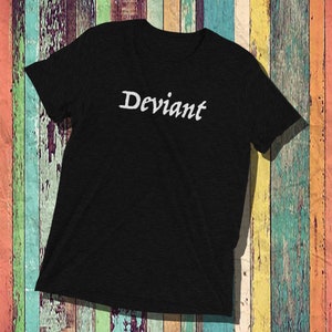 Può includere: Una maglietta nera con la parola "Deviant" scritta in lettere corsive bianche.