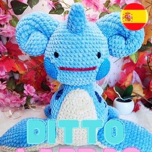 Könnte beinhalten: Ein handgefertigtes blaues Plüschtier mit großen Ohren, schwarzen Augen und einem roten Mund. Das Spielzeug hat einen weißen Bauch und blaue Flecken. Der Text "DITTO LAPRAS" wird im Bild angezeigt. Ein niedliches Katzenlogo und eine spanische Flagge befinden sich im Hintergrund.