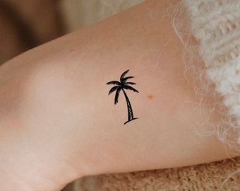 May include: A black palm tree tattoo on a person's arm.