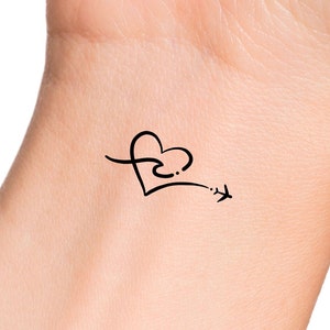 May include: A simple black line drawing tattoo design of a heart with a small airplane flying away from it.