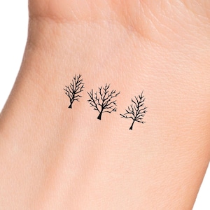 May include: Three simple black silhouette tree tattoos on a light skin tone.
