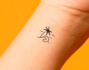 May include: A simple black line drawing tattoo of a palm tree on a wave. The tattoo is on a person's wrist.