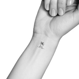 Peut inclure: Un tatouage simple en ligne noire d'un palmier sur une plage avec une vague.