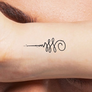 May include: A black line tattoo on a person's wrist. The tattoo is a simple design with a series of curves and a swirl at the end.